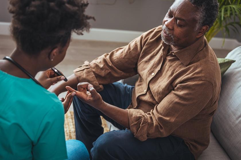 Female healthcare worker pricking senior man's finger